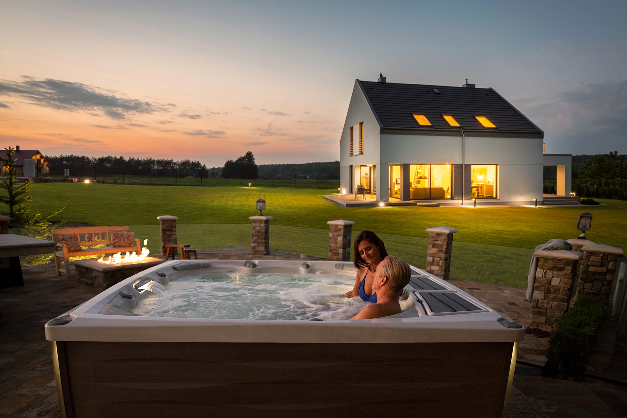 Couple enjoying their Sundance Spas hot tub at sunset