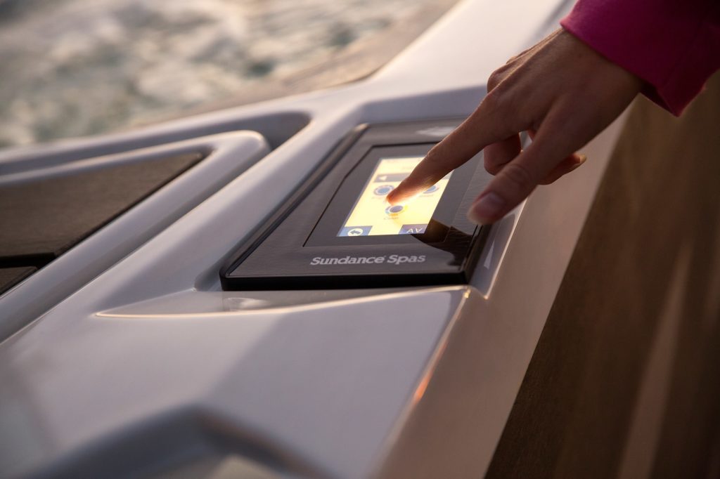 Person touching the Sundance Spas control panel on a hot tub